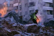 Um socorrista corre em meio aos escombros de um prédio destruído em um ataque aéreo israelense no bairro de Haret Hreik