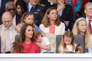 Charlotte concentrada no livro. Mia e Savannah atentas ao desfile, enquanto Louis está no colo da mamãe