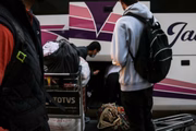 Refugiados afegãos guardam malas em bagageiro de ônibus 