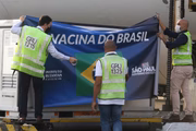 Funcionários cobrem carga de insumo de Coronavac com banner em que se lê "A vacina do Brasil"