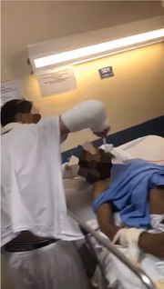Rapaz com os dois braços engessados dá comida para senhor amarrado em cama