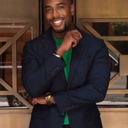 Chauncy Glover posa, sorridente, de terno preto e camisa verde