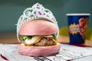 Um dos mais pedidos da <b>Dólar Furado</b> é o hambúrguer Princesa (R$ 24,90): chega num pão brioche rosa, polvilhado com pó dourado de Pirlimpimpim e leva 160g de blend da casa de filé-mignon com bacon, queijo, maionese tradicional, salada de ervas e brotinhos de rúcula. Também acompanha porção de batata