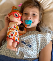 Sofia, filha de Ferrugem, posa com a boneca na cama da unidade de saúde