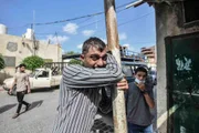 Homem palestino chora enquanto as pessoas comparecem à cerimônia fúnebre dos jornalistas palestinos Saeed Al-Taweel e Mohammad Sobh