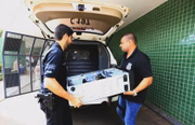 Policiais carregam material apreendido