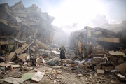 Moradora caminha perto dos escombros de edifícios residenciais após os ataques aéreos israelenses no bairro de al-Zahra, na Faixa de Gaza