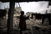 Mulher recolhe roupas após ter a casa destrída por bombardeio israelense em Deir el-Balah, na Faixa de Gaza