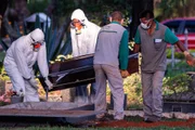 Funcionários de cemitério enterram vítima do coronavírus no DF