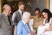 Príncipe Philip e a rainha Elizabeth paparicando Archie no colo da mãe, Meghan Markle. Harry e avó materna do bebê, Doria Ragland, também participam do momento