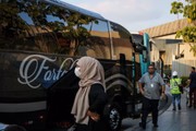Mulher afegã espera ônibus que vai levá-la para litoral paulista
