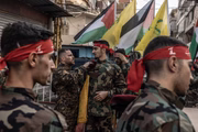 O chefe da unidade do Hezbollah ajuda um apoiador do Hezbollah a segurar sua boina