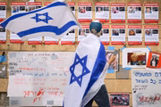 Homem segura bandeira de Israel em frente a cartazes de desaparecidos que foram sequestrados pelo Hamas - Metrópoles