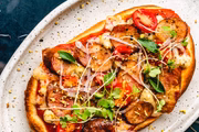 Flatbread de linguiça artesanal com molho de tomate confit, blend de queijos, tomate cereja e cebola roxa