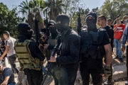 Milicianos mascarados do Hamas carregam suas armas durante o funeral de quatro jovens mortos pelo exército israelense em um ataque à cidade de Tulkarm