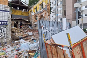 Um dos prédios do quarteirão foi parcialmente destruído e hoje tem pichações e montanha de entulho e lixo