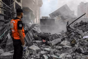 Palestinos procuram nos escombros vítimas em um prédio após ataques aéreos israelenses em Khan Yunis, Gaza