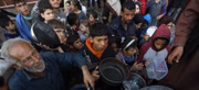 Palestinos deslocados esperam para coletar alimentos em um ponto de distribuição perto de uma escola que virou abrigo em Gaza