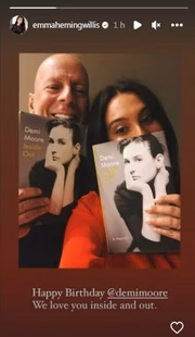 Bruce Willies e a esposa segurando a biografia de Demi Moore