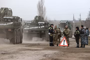 Uma coluna de veículos blindados passa por um posto policial na cidade de Armyansk, norte da Crimeia. No início do dia 24 de fevereiro, o presidente Putin anunciou uma operação militar especial a ser conduzida pelas Forças Armadas russas em resposta aos pedidos de ajuda dos líderes das Repúblicas Populares de Donetsk e Lugansk