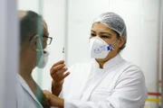 Servidora da Saúde exibe vacina preparada para ser aplicada em paciente de Goiânia