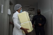Profissional de saúde da Prefeitura de Goiânia carregando caixas de vacina