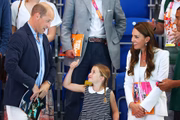 Charlotte acena para o pai, William. Ao lado, Kate sorri 