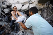 Palestinos carregam um bebê morto após os ataques aéreos israelenses em um prédio de propriedade da família Abu al-Assad
