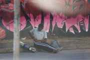 Desorientado, o homem se senta no meio-fio para fumar crack
