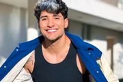 Caue Fantin posa, sorridente, com um casaco aberto para o Instagram