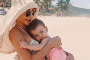Sabrina com Zoe no colo, na beira da praia 