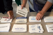 Pessoas pegando boletins de voto na seção eleitoral