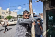 Homem palestino chora enquanto as pessoas comparecem à cerimônia fúnebre dos jornalistas palestinos Saeed Al-Taweel e Mohammad Sobh