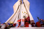 Uma vela com a imagem do papa Francisco, flores e velas deixadas pelos fiéis são vistas abaixo da escultura de São João Paulo II na entrada principal do Hospital Policlinico A. Gemelli