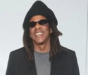 Jay-Z posa sorridente e de óculos escuros