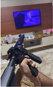 Criminoso segura fuzil em sala de casa 