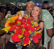 Gato Preto e Bia Miranda posam com um buquê de flores gigante