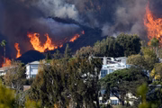 O incêndio em Palisades queima perto de casas em meio a uma forte tempestade de vento em 7 de janeiro de 2025 em Pacific Palisades, Califórnia